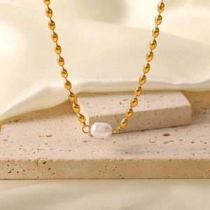 Detailed macro view of a baroque pearl pendant on a golden oval bead link chain