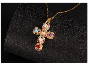 Macro shot of gold cross pendant with multicolored inlaid zircons and vintage texture