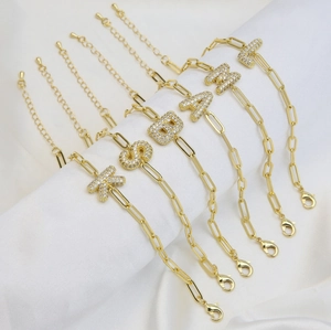 Detalle de pulseras de clip chapadas en oro de 18k con dijes de letras de circonitas