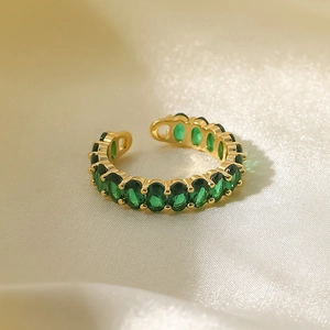 Detail of 18K gold stainless steel ring with green oval zircons on silk background