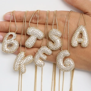 Vue détaillée de plusieurs colliers pendentifs lettres bulles dorés sertis de zircons