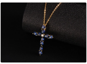 Detail of gold cross necklace featuring blue water-drop stones and a central zircon