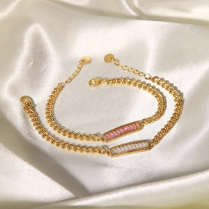 Dettaglio di bracciali a catena dorata con zirconi rosa e bianchi a taglio smeraldo