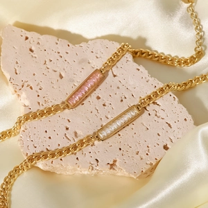 Dettaglio di bracciali in titanio dorato con zirconi rosa e bianchi su seta fine