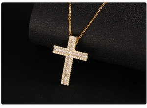 Macro view of micro-pave cubic zirconia gold cross pendant necklace on black background