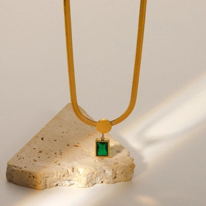 Detailed macro shot of an 18K gold-plated snake chain necklace with a green emerald gemstone