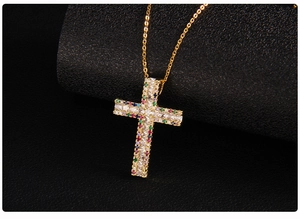 Macro detail of a gold cross pendant with micro-pave zircons and colorful gemstones