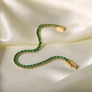 Detailed macro of gold-plated tennis bracelet featuring square green zircon stones