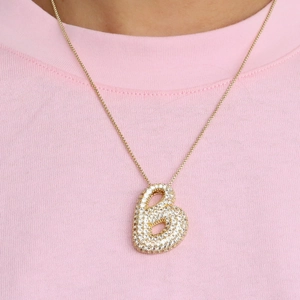 Collier avec lettre b bulle dorée et zircons cubiques brillants sur fond de tissu rose