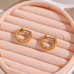 Close-up of gold stainless steel hoop earrings with star engravings and zircons