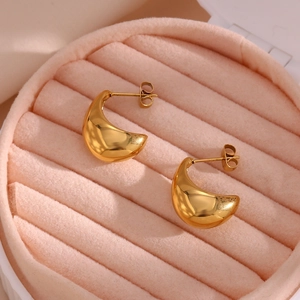 Gros plan de boucles d'oreilles dorées en forme de goutte dans un écrin en velours rose