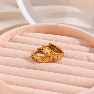 Detailed macro view of 18K gold plated hoop earrings with sunburst star zircon inlays