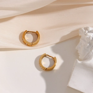 Detailed shot of gold sun zircon earrings on white silk fabric with a plaster statue
