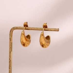 Vue détaillée de boucles d'oreilles goutte dorées sur un présentoir en métal rétro