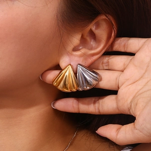Gros plan de boucles d'oreilles géométriques en or 18 carats et argent sur modèle