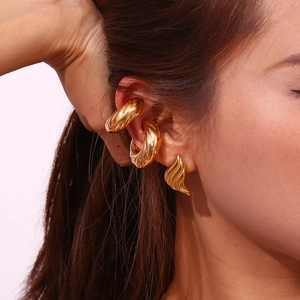Détail de boucles d'oreilles triangles dorées et de bagues d'oreilles torsadées