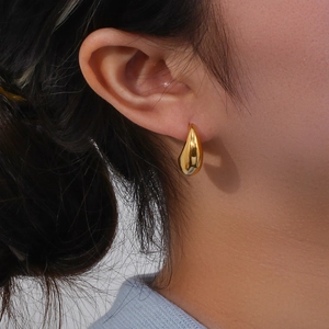 Gros plan de boucles d'oreilles gouttes dorées polies à la forme profilée sur un mannequin