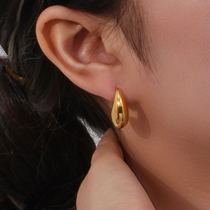 Gros plan de boucles d'oreilles goutte d'or polies pour femmes, style minimaliste épuré