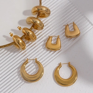Macro shot of 18K gold plated thick hoop earrings and geometric charms on textured base