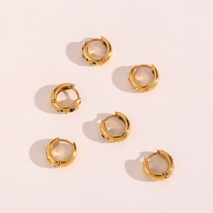 Macro detail of gold stainless steel huggie earrings with colorful zircon stones set in wide arcs