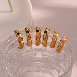 Detail of vintage gold C-shape earrings with colorful cubic zirconia on glass rim