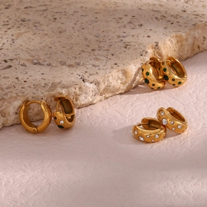 Detailed view of three pairs of chunky gold hoop earrings with green dots and cubic zirconia
