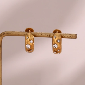 Detail of chunky gold hoop earrings with inlaid sparkling zircon stones on display