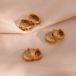 Detailed shot of three chunky gold hoop earrings with multi-color zircon on satin