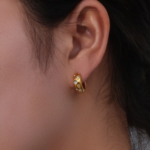 Close-up of chunky gold hoop earrings set with sparkling cubic zirconia on model ear