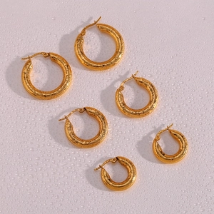 Dettaglio di orecchini a cerchio martellati placcati oro 18K con gocce d'acqua su rosa