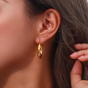 Primo piano di un orecchino a cerchio minimalista in acciaio inossidabile placcato oro 18K