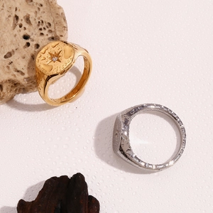 Detailed close-up of gold and silver signet rings with starburst engraving and water drops