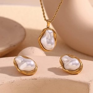 Detailed close-up of baroque pearl jewelry set with textured 18k gold-plated frames