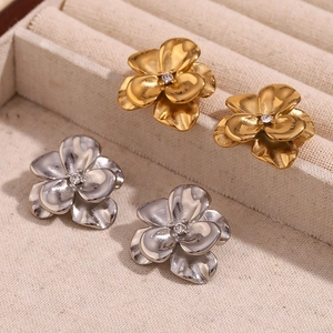 Détail de boucles d'oreilles fleurs 3D en or et argent avec strass central brillant