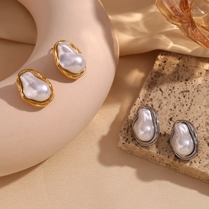 Macro detail of baroque pearl earrings with irregular gold and silver vintage metal borders