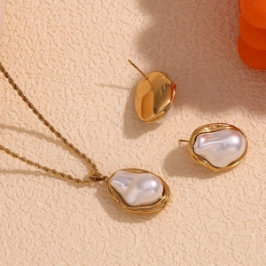 Close-up of baroque pearl necklace and earrings set with textured 18K gold-plated borders