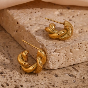 Minimalist gold twisted hoop earrings with a textured spiral design on natural stone