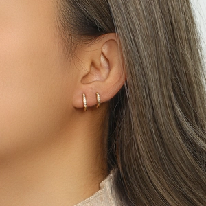 Gros plan de boucles d'oreilles huggie en acier titane doré avec zircons sur mannequin