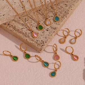 Detalle del conjunto de collar y pendientes de aro de opalo en gota sobre fondo piedra