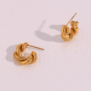 Macro detail of golden twisted hoop earrings with textured weave pattern and matte finish