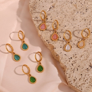 Detalle de pendientes de gota con piedra ojo de gato en varios colores sobre tela de seda