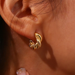 Fashionable gold twisted hoop earrings with textured finish worn by a model