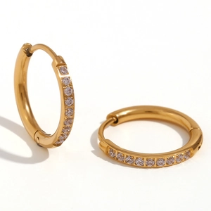Boucles d'oreilles créoles dorées en titane avec zircons micro-pavés sur fond blanc