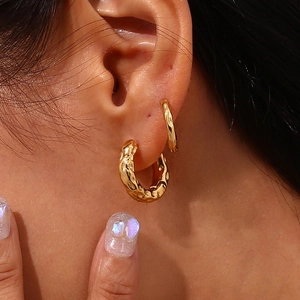 Macro view of gold hoop earrings featuring a unique hammered moon-surface texture finish