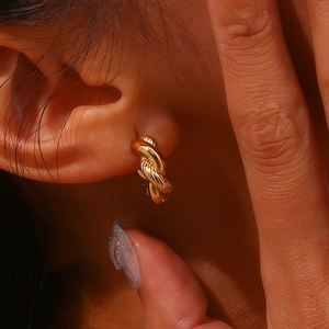 Detailed view of gold twisted cable hoop earrings with intricate braided texture design