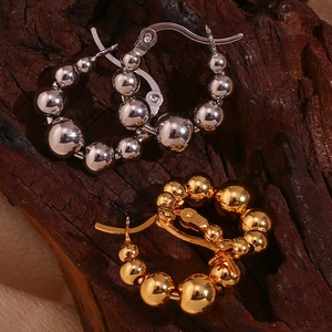 Detail view of 18K gold and silver gradient bead hoop earrings on natural wood texture