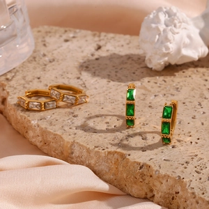 Detail of vintage gold earrings with emerald-cut green and clear zircons on stone