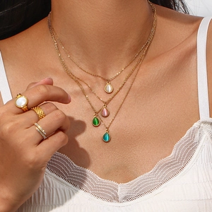 Detalle de collares dorados con colgantes de gota de colores y anillos en capas