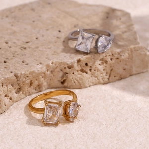 Detail of gold and silver open rings featuring emerald and pear cut zircon stones
