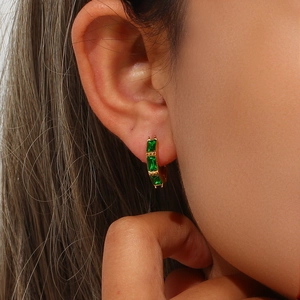 Detailed close-up of golden bamboo-style hoop earrings featuring green rectangular zircons